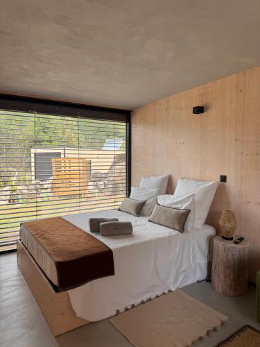 a bedroom with a large bed and a large window at Riverside Lodges - Serra da Estrela - Chão da Ribeira in Gouveia