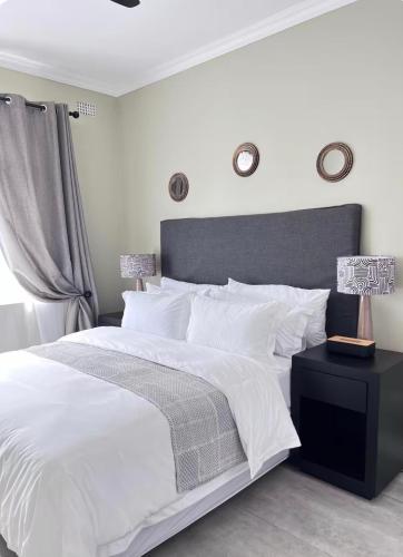 a bedroom with a white bed and a black nightstand at Heaven on Windermere in Durban