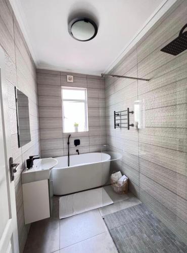 a white bathroom with a tub and a window at Heaven on Windermere in Durban