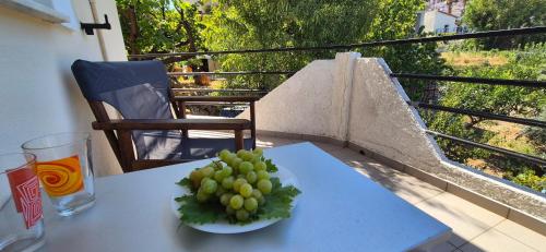 a plate of grapes on a table on a balcony at Mary's House in Vourliótai