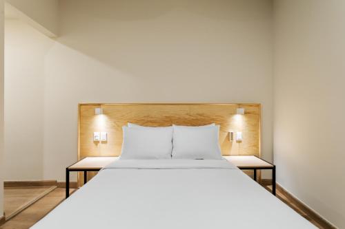 a bedroom with a large white bed with two night stands at Madero By Homirent in Querétaro