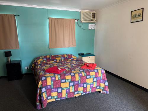 a bedroom with a bed with a colorful quilt at Coyote Inn in Cloncurry