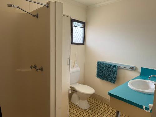 a bathroom with a toilet and a sink and a window at Coyote Inn in Cloncurry