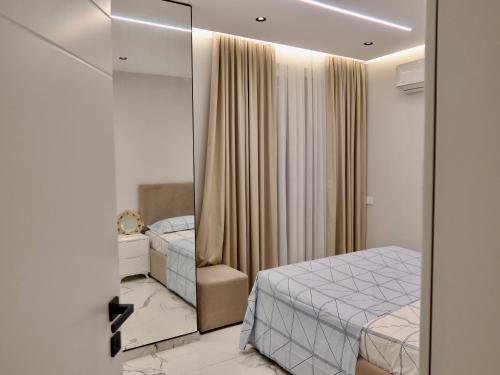a small bedroom with a mirror and a bed at Marbel Sea View in Shëngjin