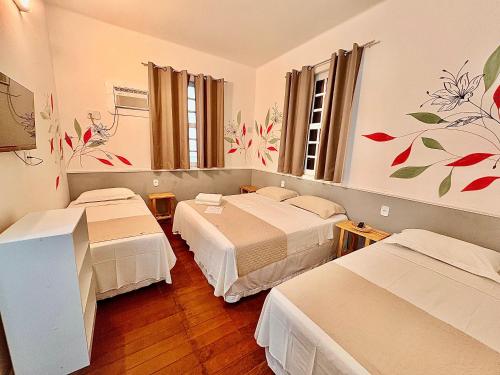 a hotel room with three beds and flowers on the wall at Pousada Flores do Farol in Salvador
