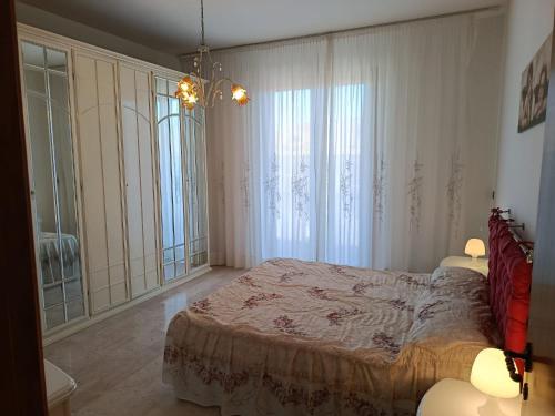 a bedroom with a large bed and large windows at Appartamenti Sole&Mare in Marotta