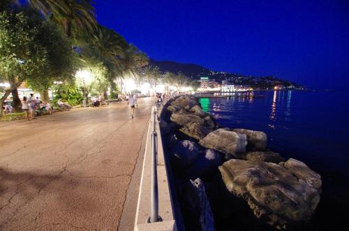 una persona che cammina lungo un marciapiede vicino all'acqua di notte di LHP Suite Rapallo a Rapallo