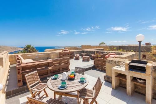 a patio with a table and chairs and the ocean at Getaway Npetto Gozitan Villa - Happy Rentals in Mġarr