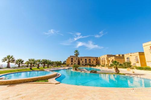 a view of a swimming pool with buildings in the background at Getaway Npetto Gozitan Villa - Happy Rentals in Mġarr