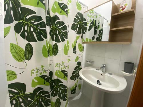 a bathroom with a sink and a shower curtain with leaves at HolidayHomePalma in Santa Maria