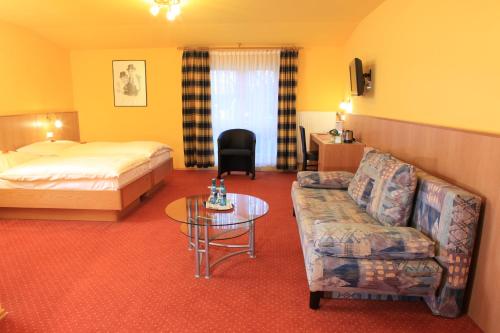 a hotel room with a bed and a couch and a table at Hotel Kasserolle in Siegburg