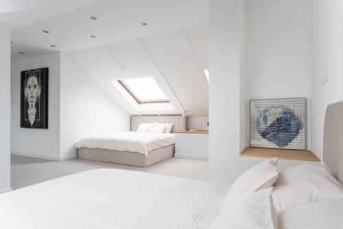 a white bedroom with two beds and a skylight at Kopernik Loft Jelenia Góra in Jelenia Góra