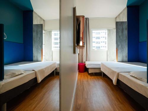 two beds in a room with blue walls and wooden floors at ibis budget Santos Gonzaga in Santos