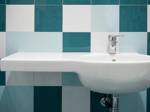 a white sink in a bathroom with blue and white tiles at Casa Isolani Luxury Rooms Piazza Maggiore 1 in Bologna