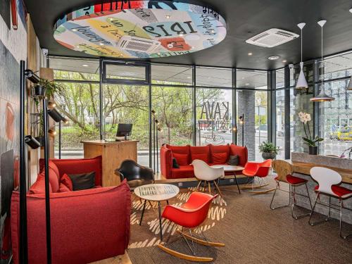 a lobby with red chairs and tables in a building at ibis Vilnius Centre in Vilnius