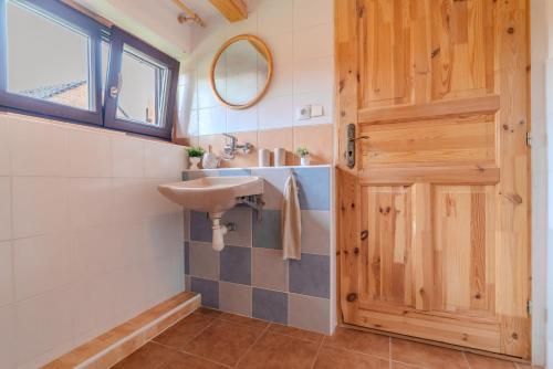 a bathroom with a sink and a wooden door at Roubenka Kubovka in Černá v Pošumaví