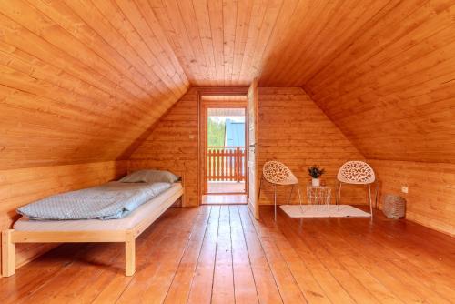 a bedroom with a bed and two chairs in a room at Roubenka Kubovka in Černá v Pošumaví