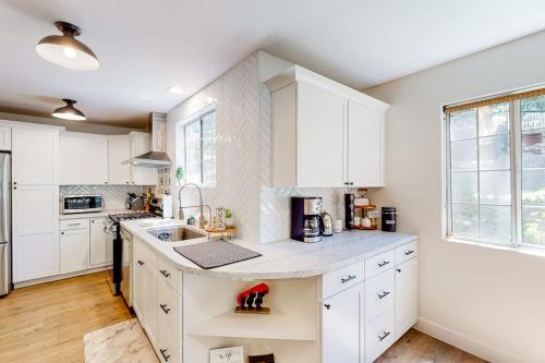 a kitchen with white cabinets and a large window at Lake Gregory Escape in Crestline