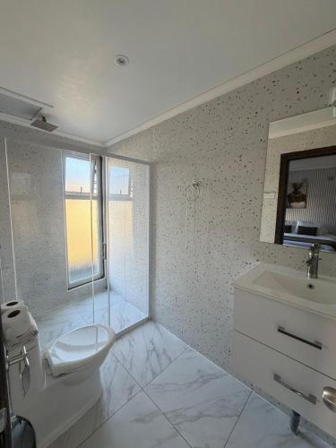 a white bathroom with a toilet and a sink at Hotel y Restaurant Mackenna in Osorno