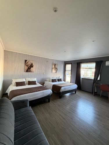 a hotel room with two beds and a couch at Hotel y Restaurant Mackenna in Osorno
