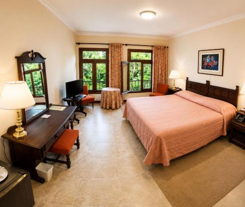 a hotel room with a bed and a desk and chairs at Hotel Aranjuez Cochabamba in Cochabamba