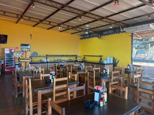 a restaurant with wooden tables and chairs and a yellow wall at Hotel Parada KM364 in Santo Antonio do Rio Abaixo