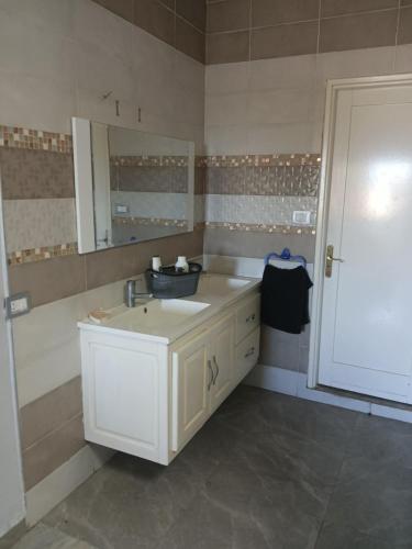 a bathroom with a sink and a mirror at Maison ras angela in Bizerte