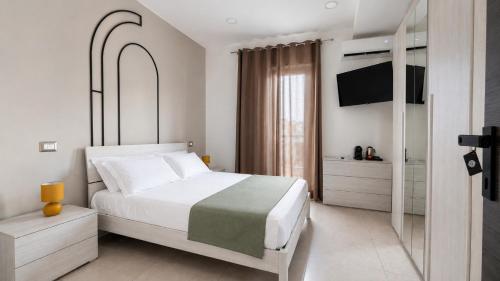 a white bedroom with a bed and a tv at The Arco Rooms in Pomigliano dʼArco
