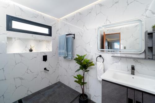 a white bathroom with a sink and a mirror at Bonbon Beach House in Liloan