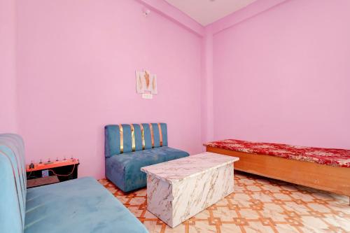 a room with pink walls and a blue chair and a table at SPOT ON S.S HOTEL in Lucknow