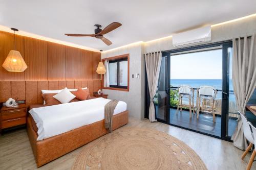 a bedroom with a bed and a balcony with the ocean at Bonbon Beach House in Liloan