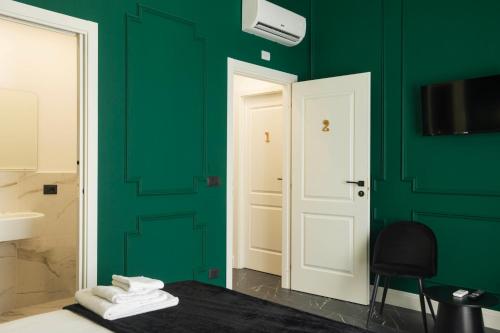 a bathroom with green walls and a door and a chair at Four Rooms Luxury Suite in Palermo