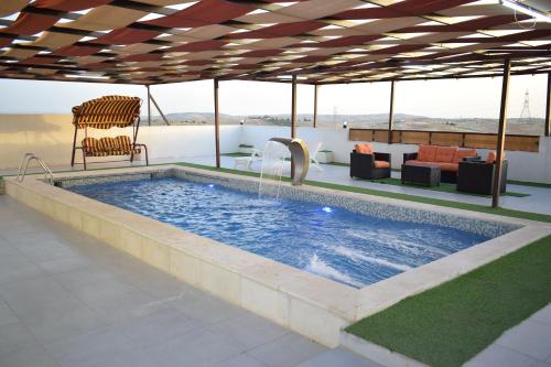 a large swimming pool with a table and chairs at La mira chalet in Madaba