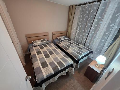 two beds in a small room with a window at Dpto 2D2B Barlovento Brisas del Sol in Talcahuano