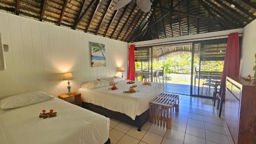 a bedroom with two beds and a balcony at Hotel Hibiscus in Papetoai