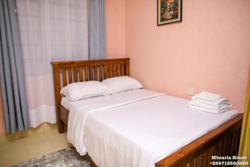 a bedroom with two beds with white sheets and a window at Mbaaria House, Meru in Meru