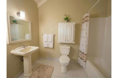 a bathroom with a toilet and a sink and a tub at Pink Sands-At Bel Air in Saint Philip