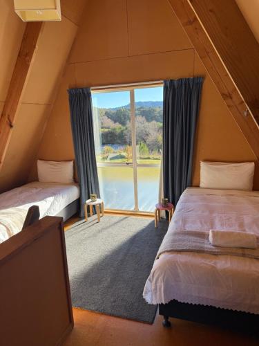 two beds in a room with a large window at Awhina's Lodge in Ohakune