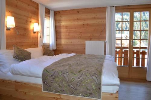 a bedroom with a large bed in a room with wooden walls at Hôtel-Restaurant Mélèze Grimentz in Grimentz