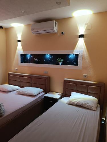 two beds in a room with lights on the wall at Grandino rooms & apartments in Ulcinj