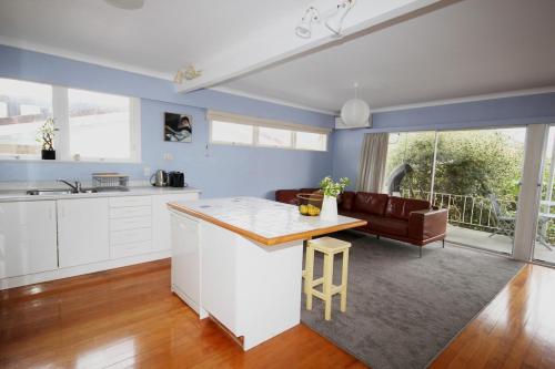 a kitchen and living room with a table and a couch at Waiwera Beach GetAway in Waiwera