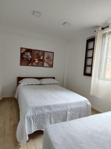 a white bedroom with two beds and a window at Recanto dos sabias AP01 in Conservatória