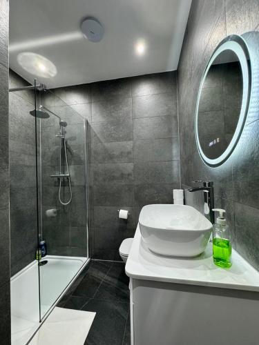 a bathroom with a sink and a shower and a mirror at Palm Bay Residency in Cliftonville