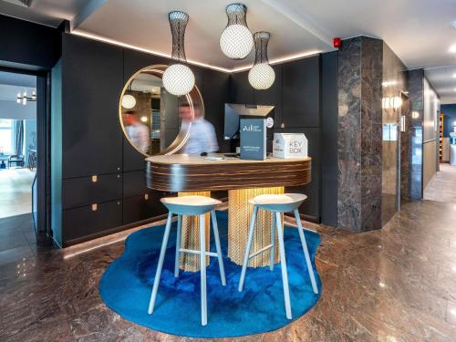 a bar with two stools and a mirror at Mercure Hotel Luebeck City Center in Lübeck