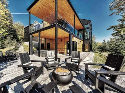 a house with chairs and a fire pit on a patio at Secret Charlevoix - River View & Spa in Les Éboulements