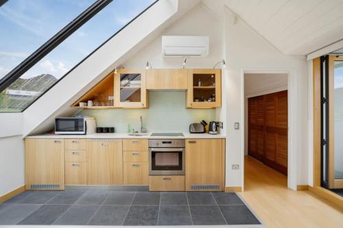 an attic kitchen with wooden cabinets and a window at Gibbston Hideaway in Gibbston