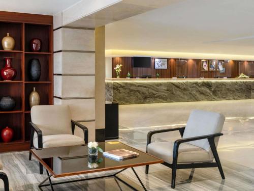a hotel lobby with two chairs and a table and a table at Anwar Al Madinah Mövenpick in Medina
