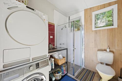 a bathroom with a washing machine and a mirror at 2 Long between breaks in Coffs Harbour