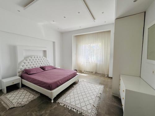 a bedroom with a bed with purple sheets and a window at Villa haut-standing avec piscine à Hammamet in Yasmine