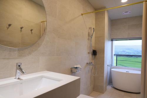 a bathroom with a sink and a tub and a mirror at Go Chishang B&B in Chishang